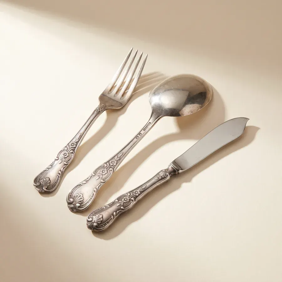 Three pieces of antique sterling silver flatware on ivory paper