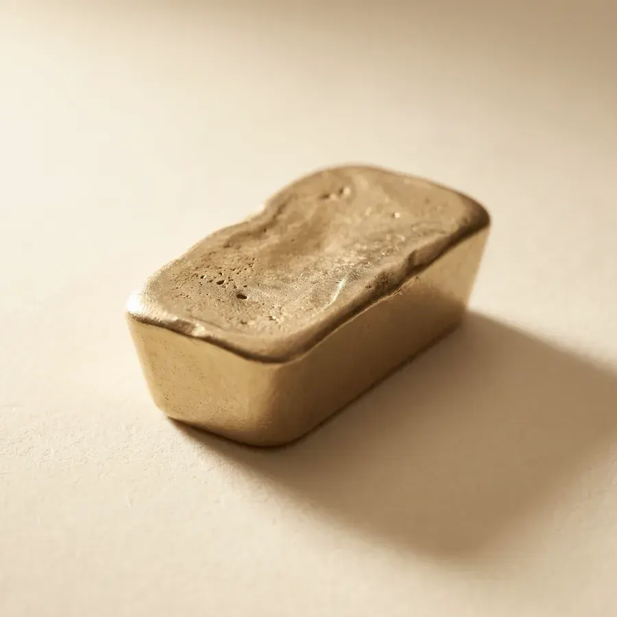 A one-ounce cast gold bar with a rough poured top surface