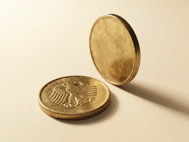 Two gold bullion coins, one lying flat and one standing on edge