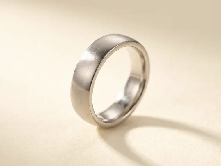 A heavy brushed platinum wedding band standing upright